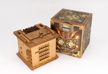 Die Rätselbox „Schrödingers Katze“ – eine hölzerne Puzzlebox mit Zifferblättern – erscheint neben einer dekorativen Box im Steampunk-Stil, ideal für Escape-Room-Fans oder Liebhaber von „Schrödingers Katze“, abgebildet auf weißem Hintergrund.