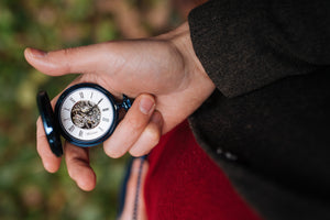 Taschenuhr aus blauem Edelstahl in einer Hand