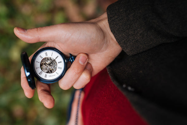 Taschenuhr aus blauem Edelstahl in einer Hand