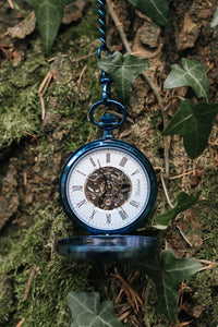 Taschenuhr aus blauem Edelstahl vor natürlichem Hintergrund