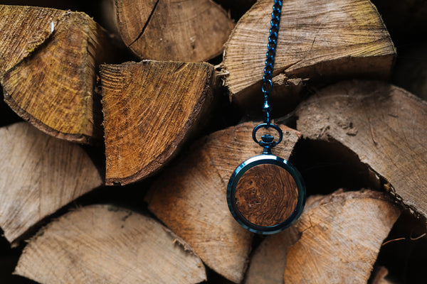 Taschenuhr aus blauem Edelstahl vor Holzscheiten