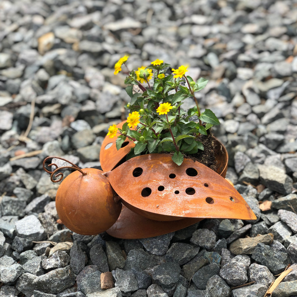 Ein Set aus zwei Edelrost-Marienkäfern mit gelben Blüten steht auf einem Bett aus grauem Kies und ist eine charmante Dekoration für jeden Raum.