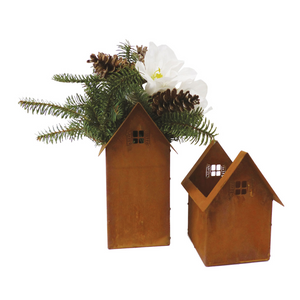 Das Set „Haus zum Bepflanzen, Edelrost“ umfasst zwei kleine hausförmige Metallbehälter – einer ist mit Tannenzweigen, Tannenzapfen und einer weißen Blume dekoriert, was ihm eine charmante Note verleiht.
