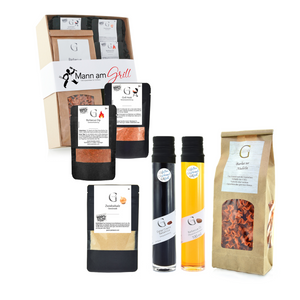 Das Geschenk-Set „Mann am Grill“ bietet ausgewählte Gewürze, Öle und Pasta in attraktiven Verpackungen – perfekt für Grillliebhaber, stilvoll vor weißem Hintergrund präsentiert.