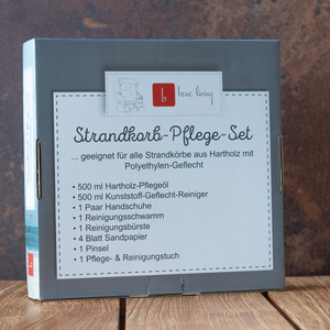 Eine graue Box mit der Aufschrift „Strandkorb Zubehör Pflegeset“, ideal zur Pflege Ihres Strandkorbs, steht auf einer Holzoberfläche mit rustikalem Hintergrund.