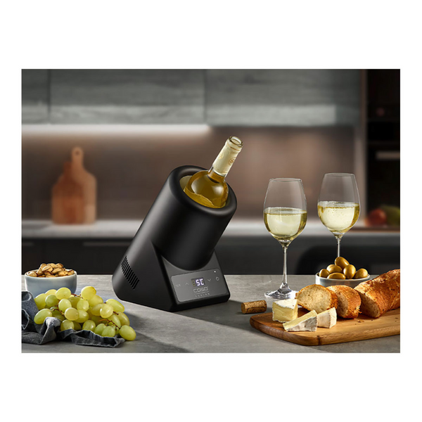 Der Flaschenkühler Vino Case Black mit Edelstahlgehäuse kühlt eine Flasche, zwei Gläser Weißwein, Trauben, Brot und Snacks stilvoll auf der Küchenzeile.