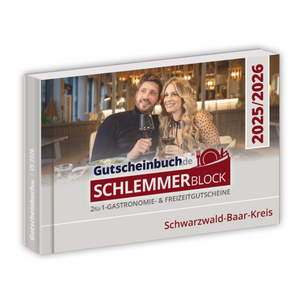 Ein Paar beim Essen und Anstoßen mit dem Gutscheinbuch Kreis Schwarzwald-Baar-Kreis 2026, das attraktive Restaurantangebote und 2-für-1-Gutscheine hervorhebt.