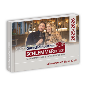 Ein Paar beim Essen und Anstoßen mit dem Gutscheinbuch Kreis Schwarzwald-Baar-Kreis 2026, das attraktive Restaurantangebote und 2-für-1-Gutscheine hervorhebt.