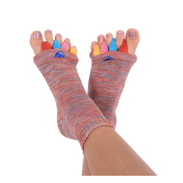 Füße tragen bunte Fußausrichtungssocken „Happy Feet“, jeder Zeh in einer andersfarbigen Tasche, dargestellt vor weißem Hintergrund – ideal als therapeutisches Hilfsmittel zur Linderung von Fußbeschwerden.
