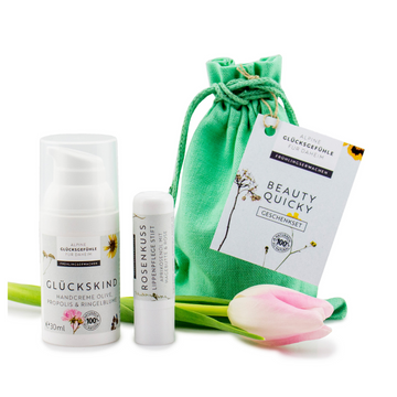 Geschenkset „Beauty-Quicky“: Hautpflege-Geschenkset mit grüner Tüte, Handcreme Olive, Lippenpflegestift, Karte und rosa Tulpe – ideal für jedes Glückskind.