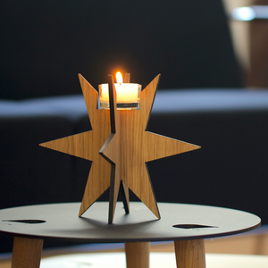 Eine brennende Kerze in einem Teelichthalter Sternenlicht steht auf einem kleinen runden Tisch und bringt gemütliche Weihnachtstradition in den modernen Raum.