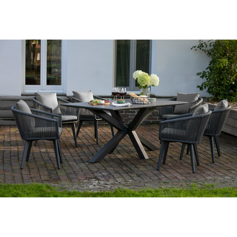 Modernes Gartenmöbelset Rope & Alu mit Tisch und sechs Stühlen, dekorativ mit Blumen, Wein und Speisen auf einer stilvollen Backsteinterrasse arrangiert.