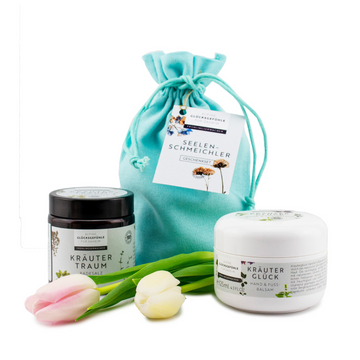 Geschenkset „Seelenschmeichler“ in einem türkisfarbenen Geschenkbeutel: zwei Gläser Badesalz Alpenkräuter und drei Tulpen auf weißem Hintergrund.