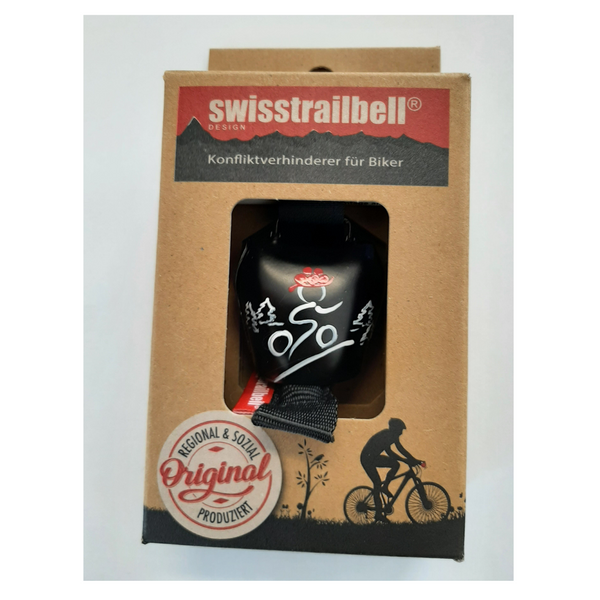 Die Fahrradglocke swisstrailbell® in Verpackung, geschmückt mit Biker- und Bergmotiven sowie deutschem Text – sorgfältige Handarbeit für stilbewusste Radfahrer.