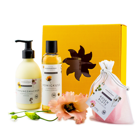Geschenkset „Sinnesfreude“ mit gelber Box, zwei Floral-Fläschchen Honigkuss Flüssigseife Honig Zitrone, einem rosa Sachet und Blumen-Deko.