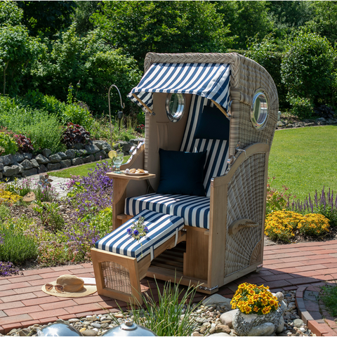 Genießen Sie entspannte Stunden im Garten mit dem Strandkorb 1-Sitzer blau-weiß – aus PE-Geflecht und Teak-Holz, inklusive blau-weiß gestreiften Kissen, Fußstütze, Snacks und Sonnenhut.