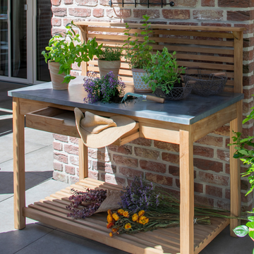 Der aus massivem Teakholz gefertigte Pflanztisch Teak bietet Platz für Kräutertöpfe, Gartengeräte und Trockenblumen auf einer sonnigen Terrasse.