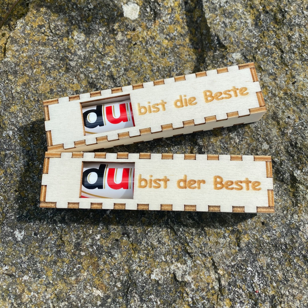 Das Schwarzwald Geschenkboxen 2er Set besteht aus zwei Holzboxen mit deutschem Text, die jeweils einen USB-Stick enthalten und im Freien auf rauem Stein präsentiert werden – eine einzigartige Verpackung, inspiriert vom Schwarzwald.