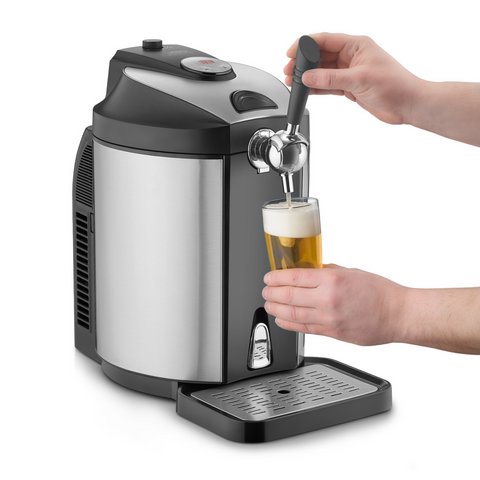 Eine Person gießt perfekt gekühltes Bier aus der Bierzapfanlage in ein Glas, sodass Schaum entsteht.